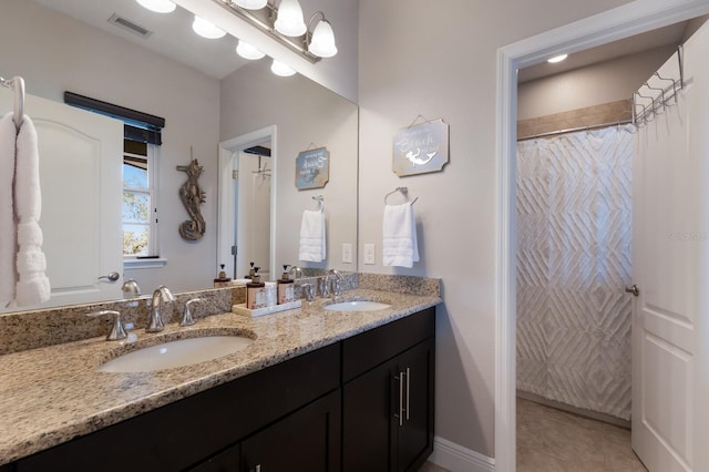 bathroom featuring double vanity, visible vents, tile patterned flooring, and a sink