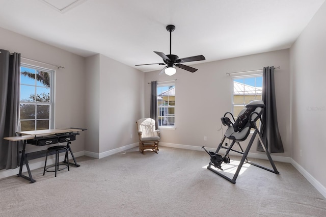 exercise room featuring baseboards, light carpet, and a ceiling fan