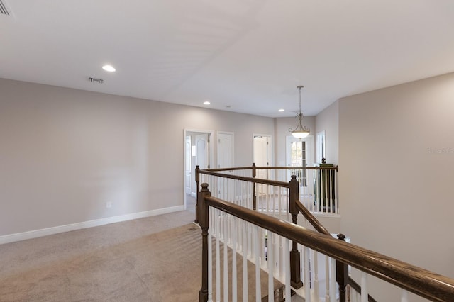 hallway featuring visible vents, baseboards, recessed lighting, carpet flooring, and an upstairs landing