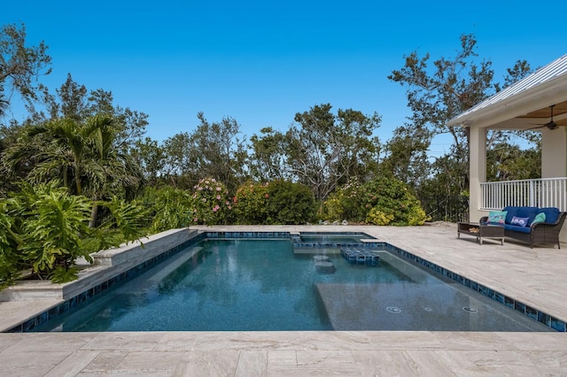 view of pool with an outdoor living space, a pool with connected hot tub, a ceiling fan, and a patio area