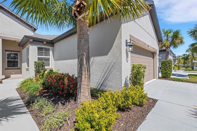 view of property exterior with stucco siding, a garage, and concrete driveway