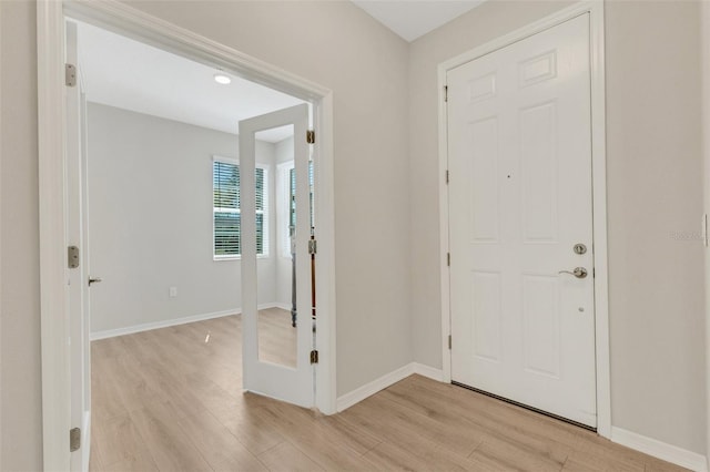 foyer entrance with light wood-style flooring and baseboards