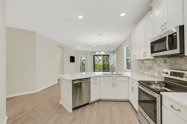 kitchen featuring a sink, stainless steel appliances, a peninsula, light countertops, and decorative backsplash