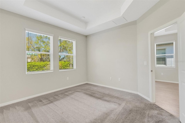 carpeted empty room featuring baseboards and a tray ceiling