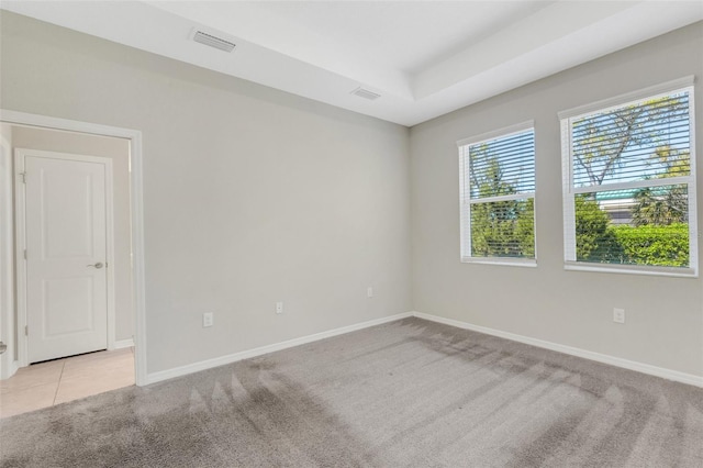 spare room featuring light tile patterned floors, visible vents, light colored carpet, and baseboards