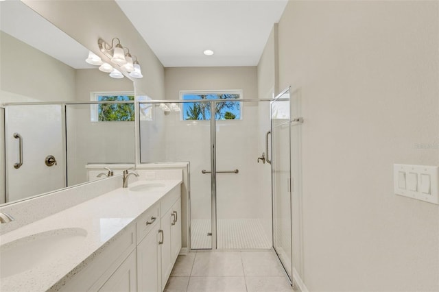 bathroom with a sink, double vanity, a shower stall, and tile patterned flooring