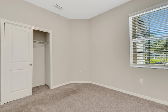 unfurnished bedroom with light carpet, visible vents, a closet, and baseboards