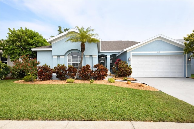 ranch-style home with stucco siding, a front lawn, driveway, roof with shingles, and a garage