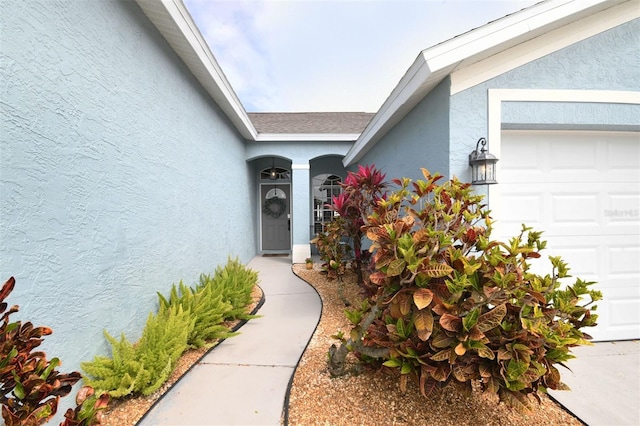 view of exterior entry featuring stucco siding and an attached garage