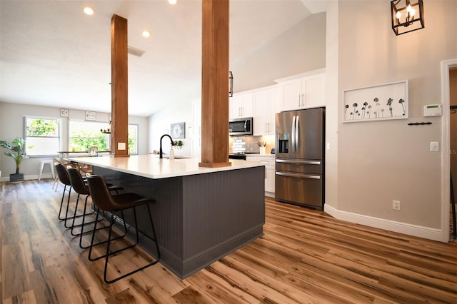 kitchen featuring a sink, tasteful backsplash, a spacious island, white cabinetry, and appliances with stainless steel finishes