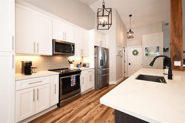 kitchen with a sink, tasteful backsplash, appliances with stainless steel finishes, and white cabinetry