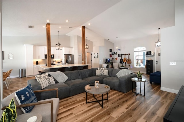 living room with visible vents, high vaulted ceiling, recessed lighting, light wood-style floors, and baseboards