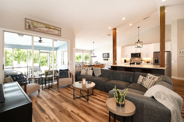 living area with recessed lighting, high vaulted ceiling, a ceiling fan, and light wood finished floors