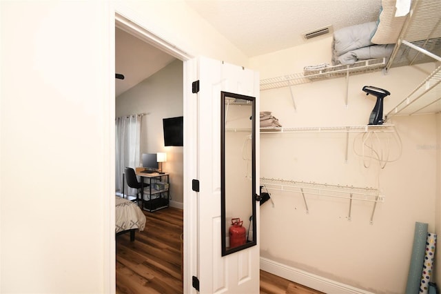 walk in closet featuring visible vents, lofted ceiling, and wood finished floors