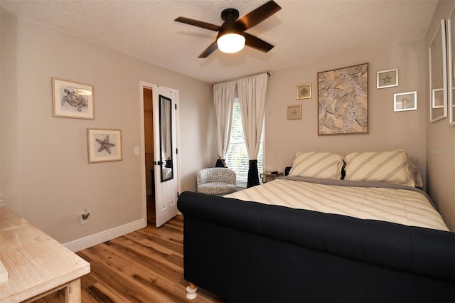 bedroom featuring ceiling fan, baseboards, a textured ceiling, and wood finished floors