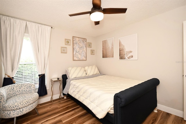 bedroom featuring a ceiling fan, wood finished floors, baseboards, and a textured ceiling