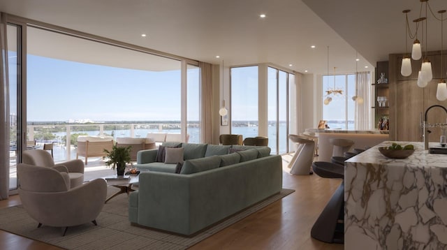 living area with recessed lighting, a water view, light wood finished floors, and expansive windows