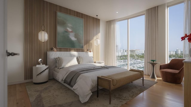 bedroom featuring a wall of windows, baseboards, wood finished floors, and a view of city