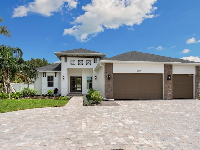 prairie-style home with decorative driveway, french doors, a garage, and stucco siding