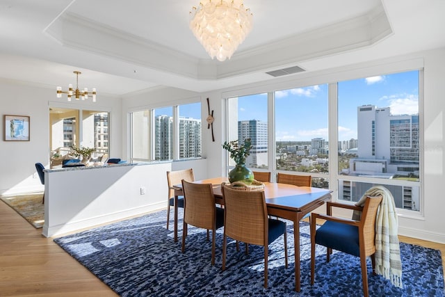 35 Watergate Dr Unit 1402, Sarasota, FL 34236 - dining space featuring visible vents, a raised ceiling, an inviting chandelier, and wood finished floors