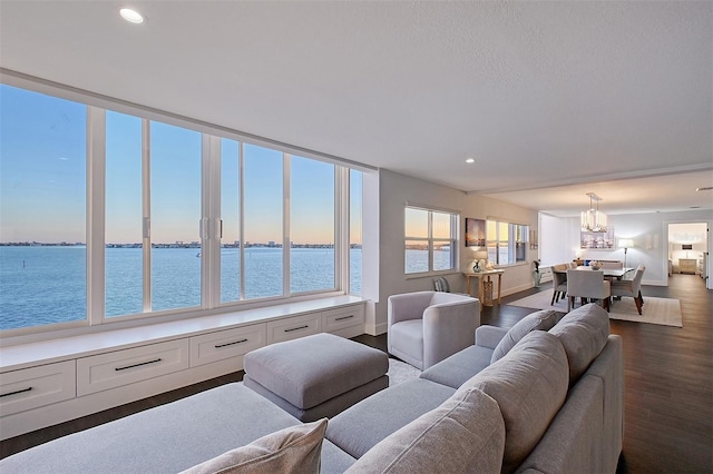 living room with a water view, dark wood-style floors, recessed lighting, baseboards, and a chandelier