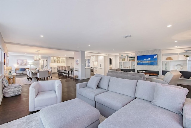 living room with built in shelves, wood finished floors, visible vents, recessed lighting, and a notable chandelier