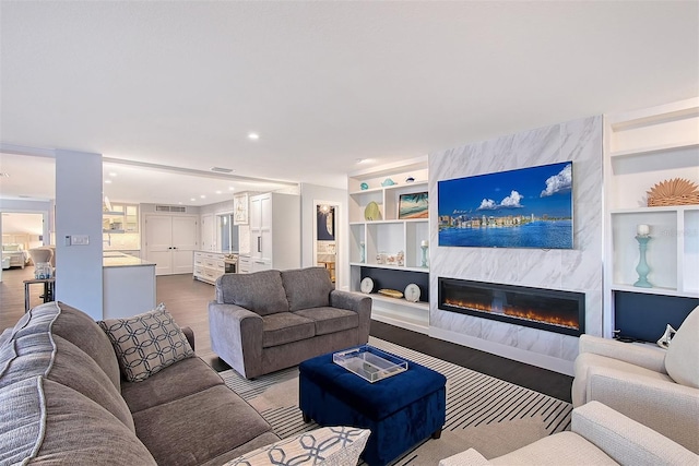 living area with visible vents, dark wood-type flooring, built in features, recessed lighting, and a fireplace