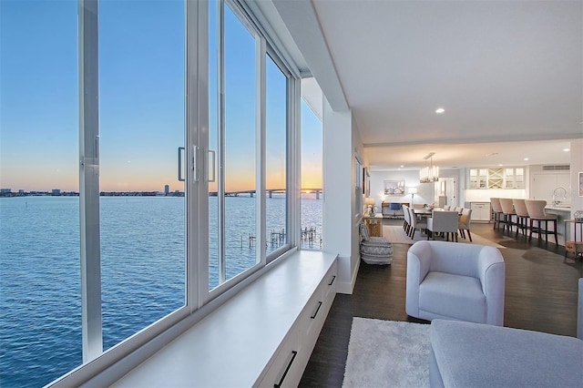 living room with recessed lighting, dark wood-style floors, and a water view