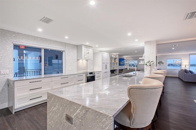 kitchen with visible vents, electric stove, a sink, open floor plan, and dark wood finished floors