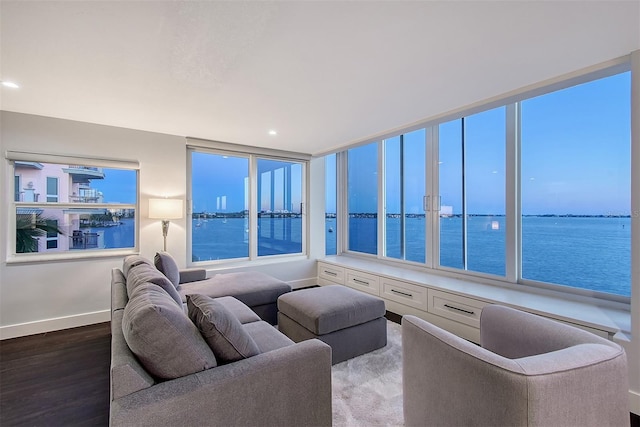 living room featuring recessed lighting, baseboards, wood finished floors, and a water view