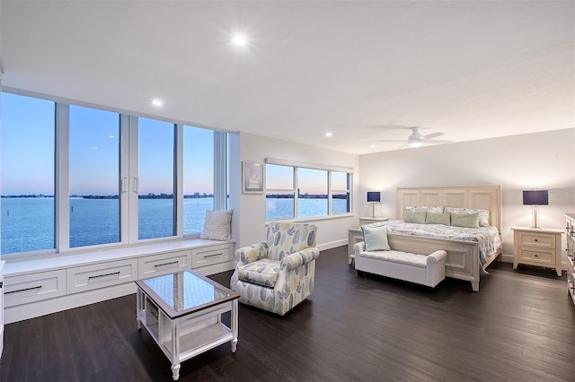 bedroom featuring dark wood finished floors, baseboards, and a water view