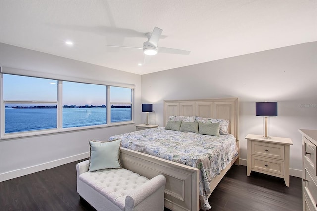 bedroom with ceiling fan, baseboards, dark wood-style floors, and a water view