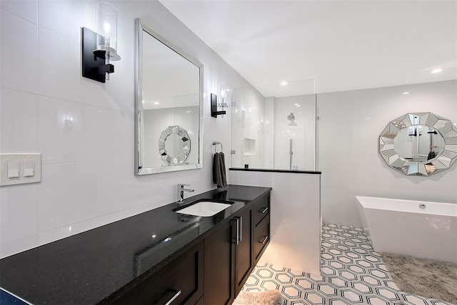 full bathroom featuring a freestanding bath, tile walls, vanity, and a walk in shower