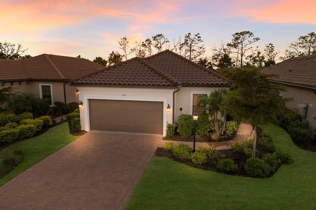 view of front of property featuring stucco siding, a tiled roof, decorative driveway, and a garage