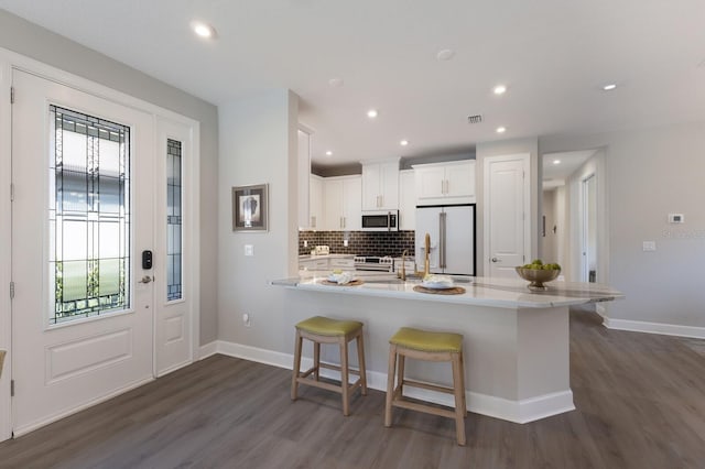 kitchen with a kitchen breakfast bar, high quality appliances, a healthy amount of sunlight, and light countertops