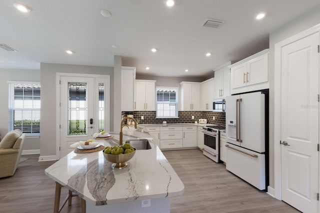 kitchen featuring white appliances, light stone countertops, visible vents, a peninsula, and tasteful backsplash