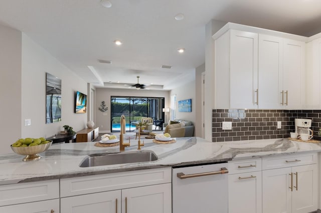 kitchen featuring light stone countertops, white dishwasher, a sink, white cabinets, and open floor plan