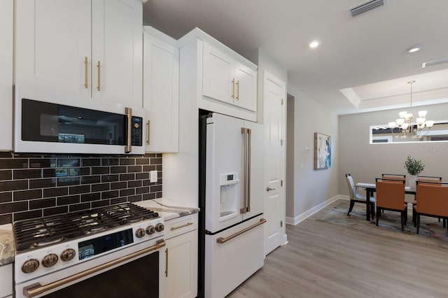 kitchen with tasteful backsplash, visible vents, an inviting chandelier, white appliances, and white cabinetry