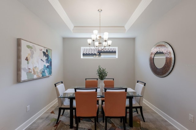 dining room featuring baseboards, a raised ceiling, and an inviting chandelier