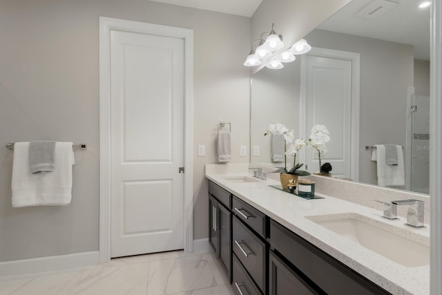 full bath featuring double vanity, marble finish floor, baseboards, and a sink