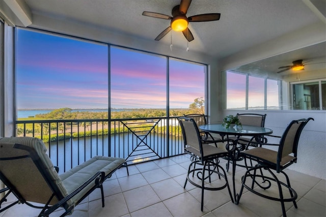 sunroom featuring a ceiling fan and a water view