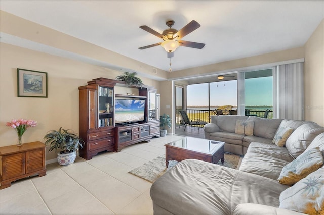 living room featuring baseboards, light tile patterned flooring, and a ceiling fan