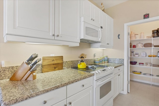 kitchen featuring white appliances, white cabinets, light tile patterned flooring, and light stone countertops