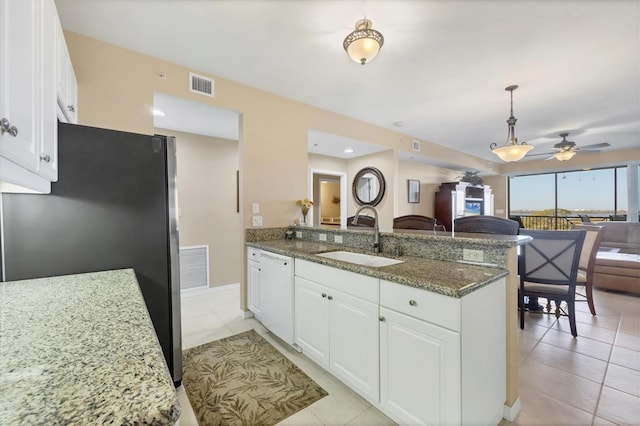 kitchen with a sink, freestanding refrigerator, a peninsula, dishwasher, and ceiling fan