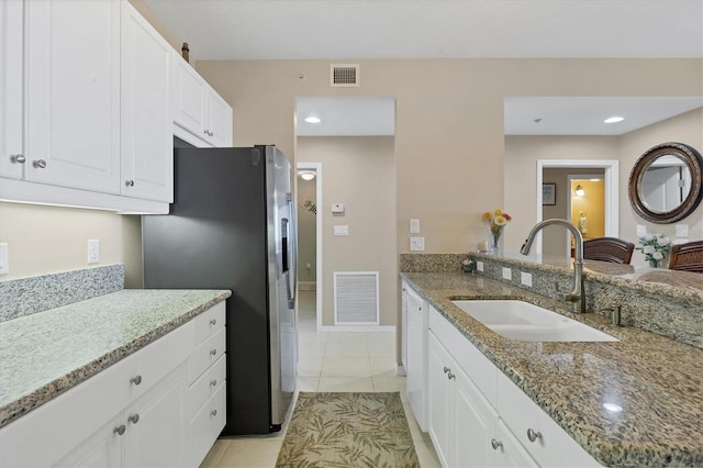 kitchen with a sink, visible vents, light stone countertops, and stainless steel refrigerator with ice dispenser