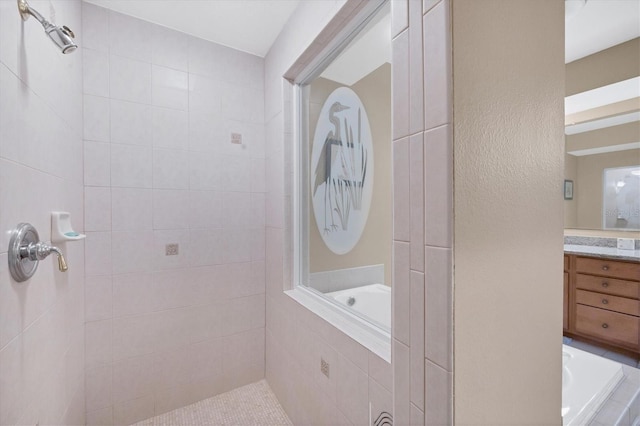 bathroom featuring tiled shower, vanity, a garden tub, and a textured wall