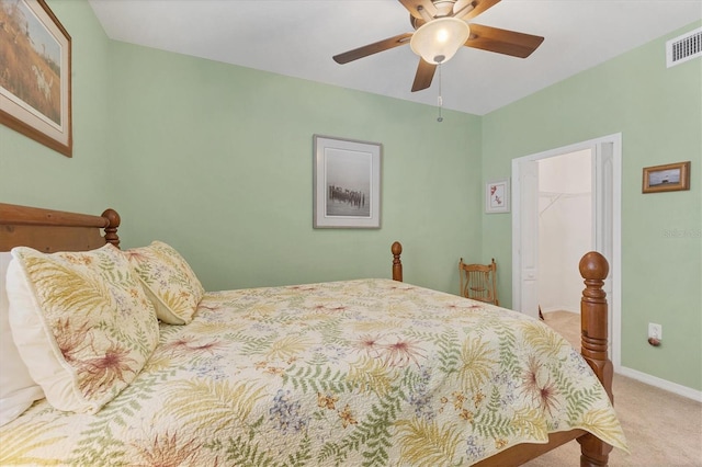 carpeted bedroom with a ceiling fan, baseboards, visible vents, a closet, and a walk in closet