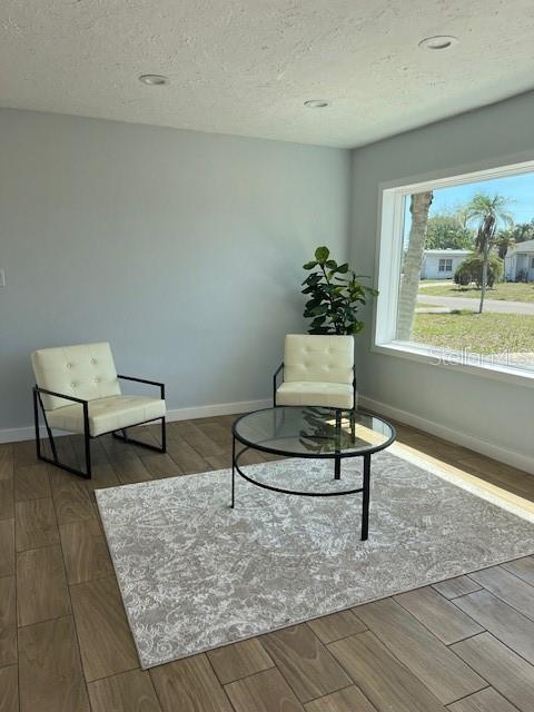 sitting room featuring wood finish floors, baseboards, and a textured ceiling