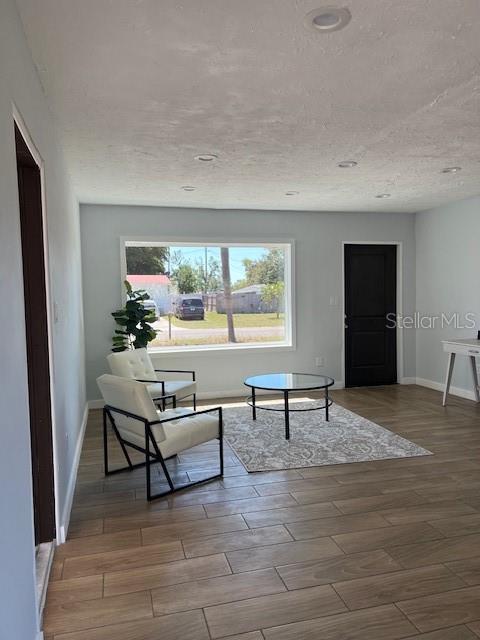 living area featuring baseboards, a textured ceiling, and wood finished floors