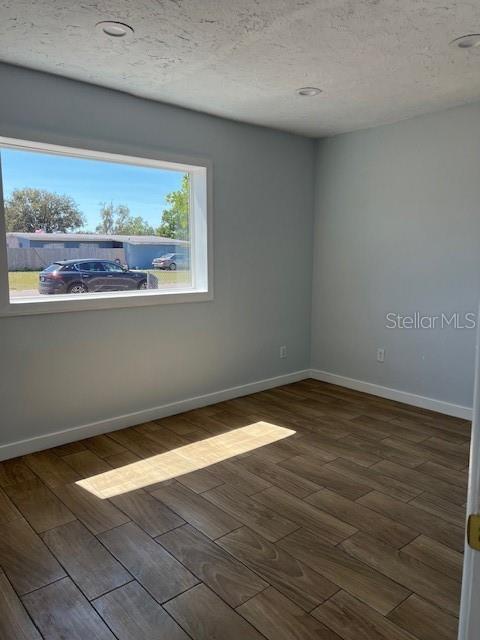 spare room with wood finished floors, baseboards, and a textured ceiling